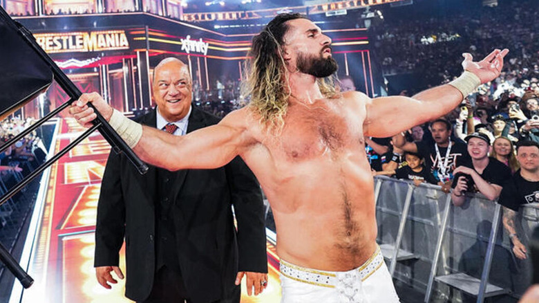 Rollins brandishes a steel chair as he leaves WrestleMania 41 victorious, with a smiling Paul Heyman behind him.