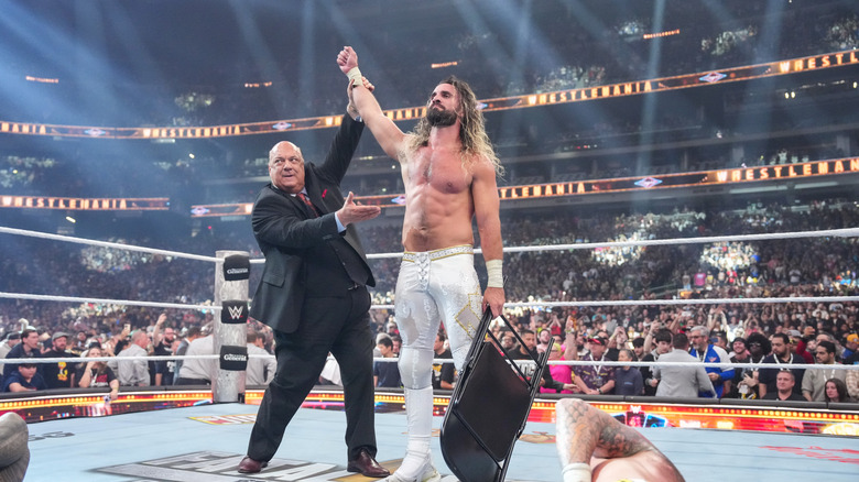 Paul Heyman raising Seth Rollins' arm